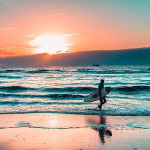 Surfeur sur la plage de Scheveningen avec le coucher du soleil