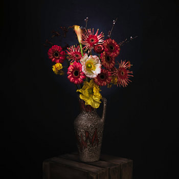 Schilderachtig stilleven van rode en gele bloemen in een retro vaas.