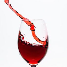 Le vin rouge coule dans le verre à vin sur Roland Brack