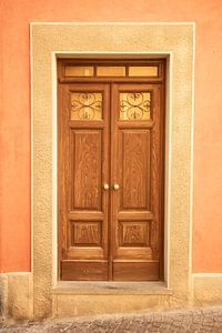 Die braune Tür und die orangefarbene Wand in Barolo, Italien - sommerliche Straßen- und Reisefotografie.