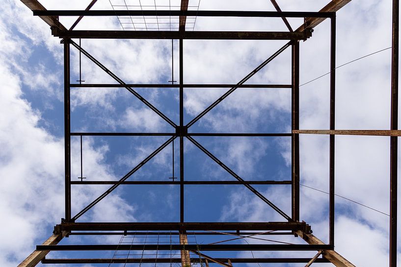 Urbex Symmetrie - verrostete Metallkonstruktion vor einem blauen Himmel mit Wolken von Photo Henk van Dijk