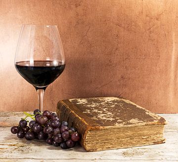 glas rode wijn op een tafel met een oud boek
