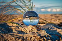 View through the glass ball on the beach. Sea and sky in background
