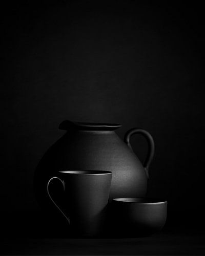 Zwart stilleven van een kan met een kopje en een schaaltje