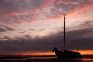 Klassiek platbodem zeilschip drooggevallen op het Wad tijdens een prachtige zonsondergang. van Sjoerd van der Wal
