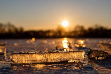 Eisbrocken auf einem gefrorenen See während eines warmen Sonnenaufgangs von Kim Willems