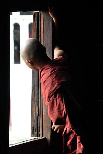 Monnik kijkt naar buiten vanuit zijn houten klooster van Shwe Yaunghwe