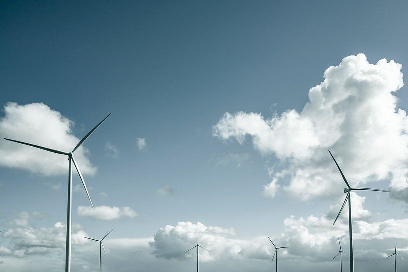 Windturbine met draaiende wieken met een stormachtige blauwe lucht in de verte van Sjoerd van der Wal Fotografie