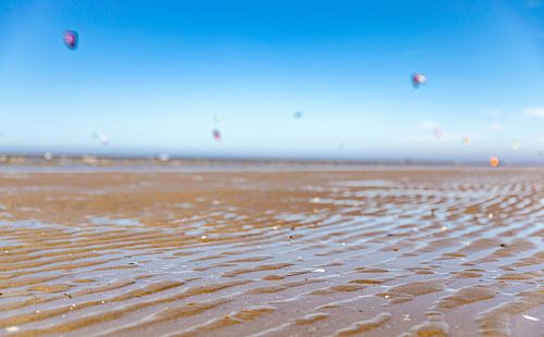 Close-up nat zand met kitesurfers