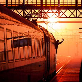 Silhouette van trein machinist die vertreksein geeft tijdens zonsondergang van Rob Kints