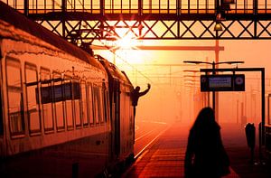 Silhouette van trein machinist die vertreksein geeft tijdens zonsondergang van Rob Kints