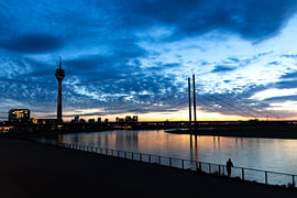La ligne d'horizon de Düsseldorf au coucher du soleil, avec la Rheinturm, la promenade et le pont Rheinkniebrücke sur Your Happy Life