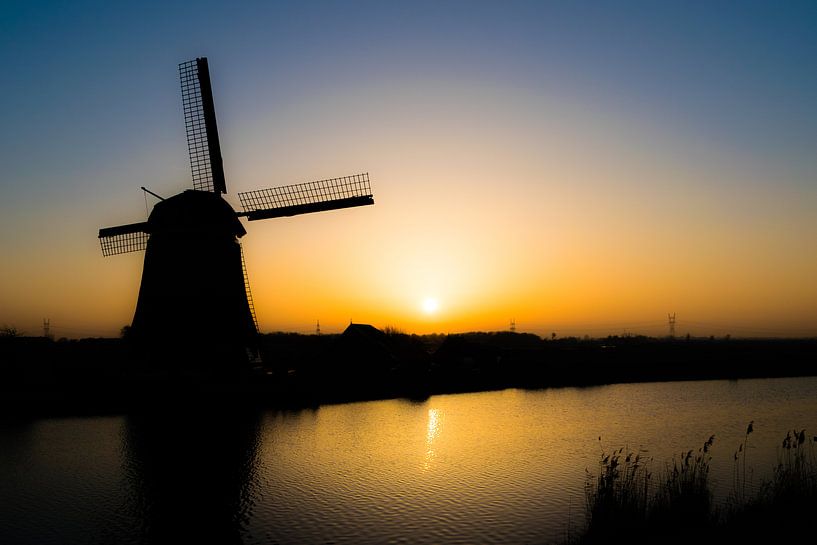 Silhouet van molen aan het water bij ondergaande zon van Sander de Vries