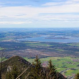 Panoramic view over a green landscape with mountains in the foreground and the large Chiemsee lake in the distance by Thomas Heitz