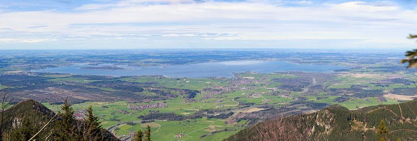 Panoramic view over a green landscape with mountains in the foreground and the large Chiemsee lake in the distance by Thomas Heitz