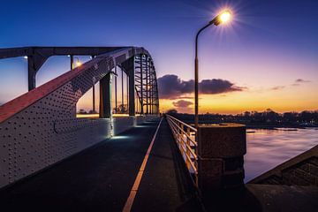 Die Wilhelminabrücke bei Nacht in Deventer mit untergehender Sonne.
