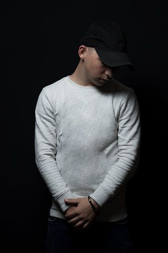 Tiener met zwarte pet kijkt naar beneden