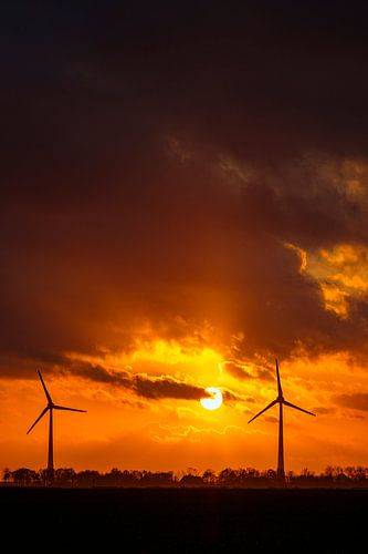 Windturbines in een kleurrijke herfstzonsondergang met zonlicht achter de wolken