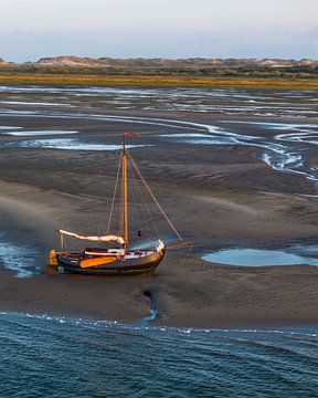 Gestrand Zeilschip bij Zonsopkomst: Waddenzee in Betoverend Licht van Ewold Kooistra