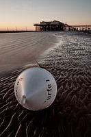 Paalwoning in de zonsondergang met boei op de voorgrond, St. Peter-Ording
