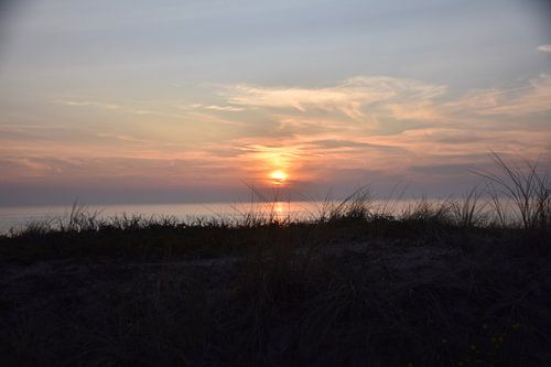Zicht over de duinen op de zonsondergang.