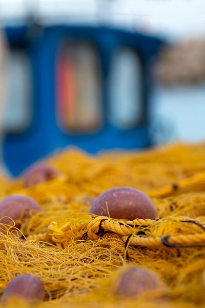 Colorful fishing net and boat in harbor by Sia Windig