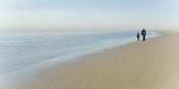 Vader en zoon lopen langs het strand van Texel