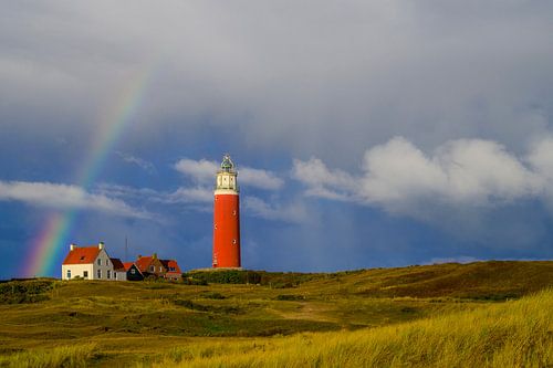 Texelse vuurtoren in de duinen met een regenboog tijdens een stormachtige ochtend