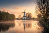 Peaceful Sunrise Over a Misty River with Traditional Dutch Windmill in the Netherlands