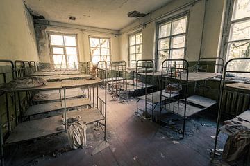 Slaapzaal met stapelbedden in verlaten kleuterschool van Tsjernobyl van Robert Ruidl