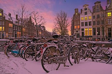 Besneeuwde fietsen langs de grachten in Amsterdam bij zonsondergang in Nederland in de winter van Eye on You