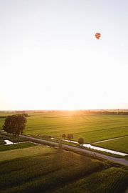 Hot air balloon floats above a Dutch landscape by Moniek Kuipers