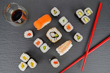 Sushi op zwart serveerbord geserveerd met rode eetstokjes