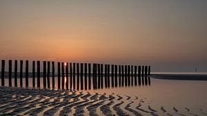 Die Sonne versinkt hinter den Wellenbrechern von Bram van Broekhoven
