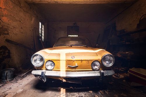 Fiat jaune dans un garage abandonné.