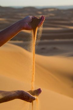 Handen spelen met Sahara zand.