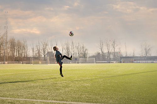 child rehearses with ball on soccer field