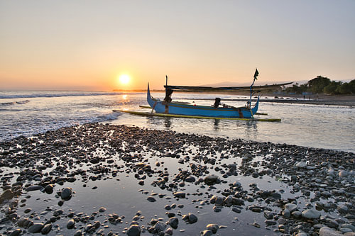 A jukung fishing boat on the coast at sunset in Medewi, Bali