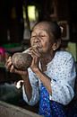 Alte Frau raucht traditionelle Stumpen Zigarre vor ihrem Haus in Baghan in Myanmar von Wout Kok Miniaturansicht