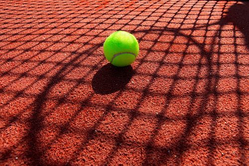 tennisbal in de schaduw van een tennisnet en een racket