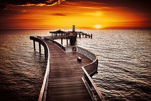 Sonnenaufgang hinter der geschwungenen Seebrücke Koserow auf der Insel Usedom in goldenem Ton getaucht