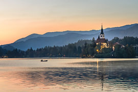 Bled im Morgenglühen - Boot auf dem Wasser von Daan Duvillier | Stimmungsvolle Stadt- und Landschaftsfotos