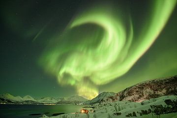 Haus in einem Fjord in Norwegen unter Polarlicht. von Marco Verstraaten