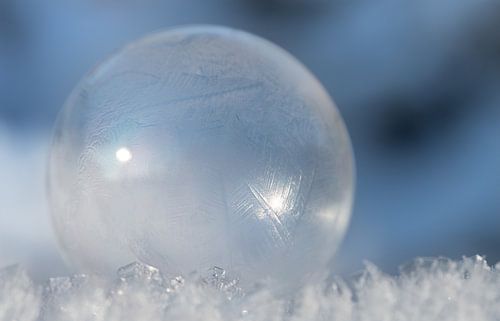 bevroren zeepbel voor blauwe lucht op sneeuw