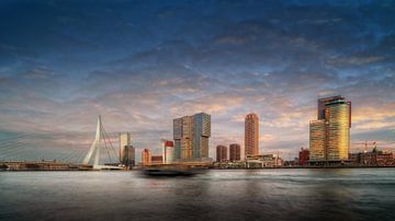 Stadtbild von Rotterdam am Abend mit Gebäuden und Boot im Vordergrund.