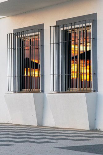 Zonsondergang weerspiegeld in een raam van een witte gevel. Rota, Costa de la Lutz, Cádiz, Andalusië, Spanje
