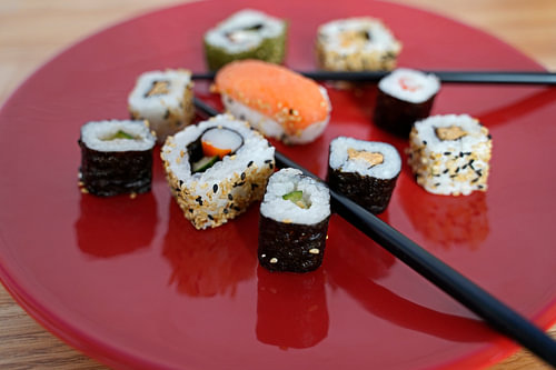 Sushi op een rood bord met eetstokjes