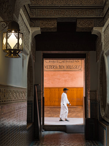 Ein Mann in einer Jeleba geht am Eingang der Medersa Ben Youssef in Marrakesch vorbei