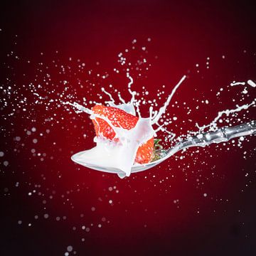 Een lekkere, rijpe, rode aardbei valt op een eetlepel melk van Photo Art Thomas Klee