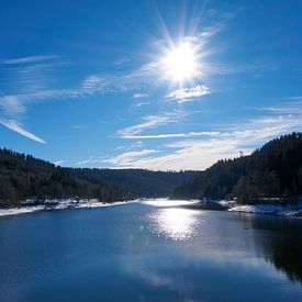 Bevroren rivier met sneeuw en ijs in zonneschijn onder blauwe hemel in Nagoldtalsperre van creativcontent